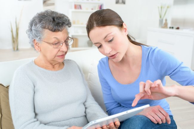 mother and daughter with tablet computer sitting on the couch