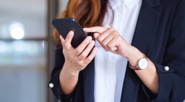 Closeup image of a businesswoman holding and using mobile phone