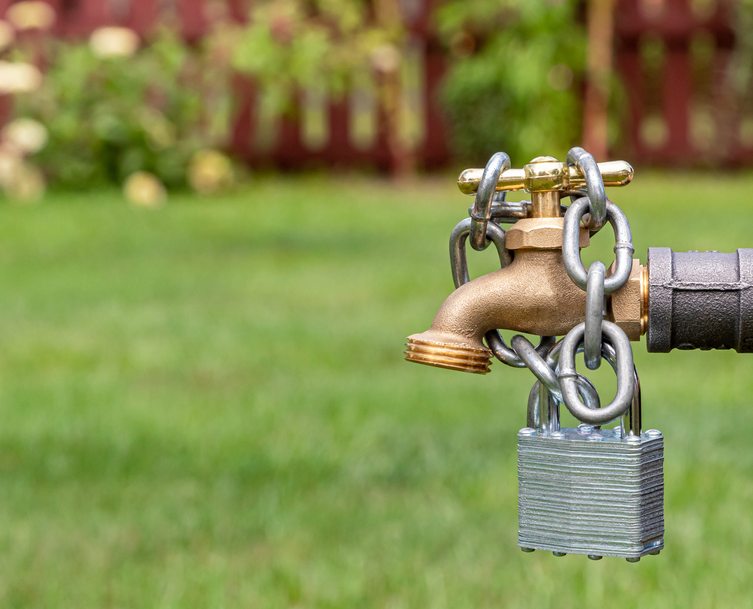 Outdoor water faucet with lock and chain. Water restriction, sup